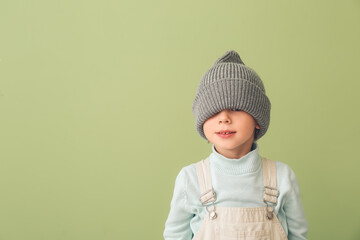 Wall Mural - Funny little boy in warm hat on color background