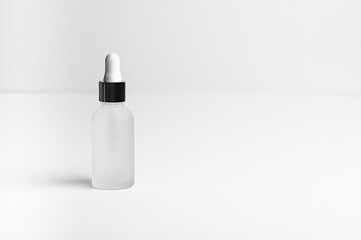 Wall Mural - Face serum in a white glass package, bottle on a white neutral background. Natural treatment for dry skin with oils, vitamins and collagen. Packaging of cosmetic beauty product, pack shot, copy space