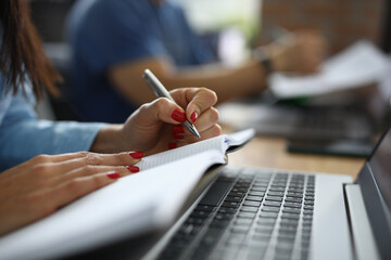 Female hands hold pen and diary next to laptop at work table. Training profession copywriter online concept