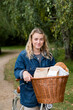 © Mint Images - Young blond woman on bicycle with basket, smiling at camera.