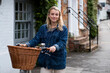 © Mint Images - Young blond woman on bicycle with basket, looking at camera.