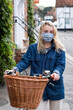 © Mint Images - Young blond woman wearing face mask on bicycle with basket, looking at camera.