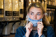 © Mint Images - Young blond woman wearing face mask, shopping in waste free wholefood store.