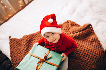 Wall Mural - A boy holding a large box in a green package and a bow with a gift. Christmas mood.