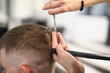 © Тихон Купревич - Master's male head holds comb in his hands and cuts his hair with scissors. Stylish and fashionable hairstyles in beauty salons concept