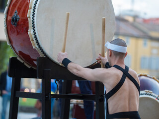 Man with Headband Playing Vertical Drum of Japanese Musical Tradition during a Public Outdoor Event