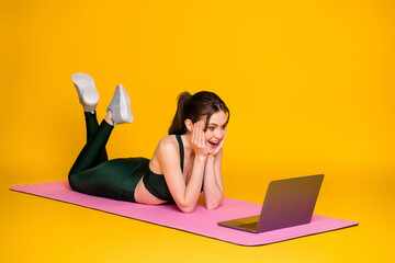 Poster - Full body size profile side view of nice glad cheerful amazed girl watching online tutorial lying on mat isolated on bright yellow color background