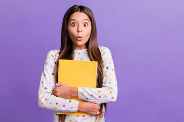 Poster - Photo portrait of amazed shocked girl hugging yellow book wearing sweater staring isolated on bright purple color background