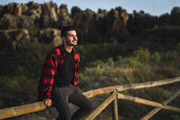 Closeup focus shot of a young man sitting on a railing at a park