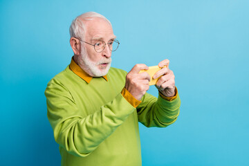 Poster - Profile photo of shocked grandpa hold telephone watch movie wear glasses green pullover isolated blue color background