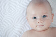 © Vladimir - Baby with blue eyes portrait lying on bed
