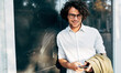 © iuricazac - A businessman in eyewear smiling broadly posing outdoors. Male entrepreneur resting in the city street. Smart guy in casual wears spectacles with curly hair walking outside after work