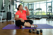© Prasit Rodphan - Asian fat woman fights overweight in the gym, doing heavy fitness exercises for future strong body. Obese person tired and drink water.