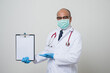 © Chanakon - Asian bald Doctor in white coat, stethoscope, blue glove wearing face mask.pointing hand to clipboard isolated on white background.