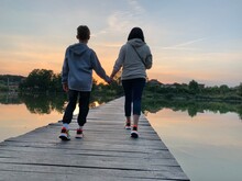 Boy With Mom On A Forest Lake. Child With A Woman On A Wooden Pier. Two People Cross The Pond Over The Bridge.