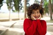 © Roquillo - Young beautiful Arab woman standing outdoors wearing red sweater looking at copyspace having thoughts about future events