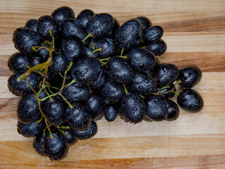 A bunch of ripe grapes lies on a wooden board.