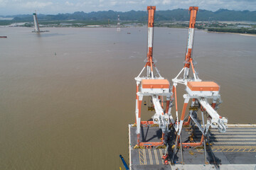 Aerial view, top view cargo ship port in the export, import by ship business, and logistics international goods. Logistics and transportation of container cargo ship working crane bridge in shipyard