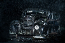Abandoned And Rusty Car Wreck Standing In A Forest In The Rain