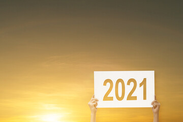 Silhouette of hand-holding paper with 2021 text for Happy New Year 2021.