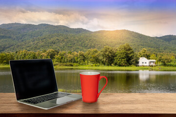 cup of coffee, a computer on a wooden table in the nature park on a sunny afternoon with a copy space,