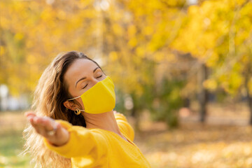 Poster - Happy woman wearing protective mask in autumn park