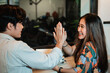 © Odua Images - young man and girls with high five when meet in the coffee shop