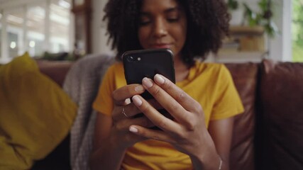 Wall Mural - Shot of young woman sitting on sofa holding mobile in her hand checking messages