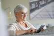 © goodluz - Mature woman with white short hair and eyeglasses connected with smartphone