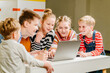 © Iryna - A group of happy smiling school children of different ages working on joint project about eco-friendly forms of renewable energy lesson.. Male and female pupils using laptop comuter.