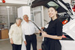 © prostooleh - Senior in a car salon. Old couple buying the car. Elegant woman helps a old people buy a car.
