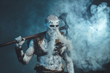 Nordic undead in dark armour with fur and naked torso with cold breath and huge axe on his shoulder in frosty fog.