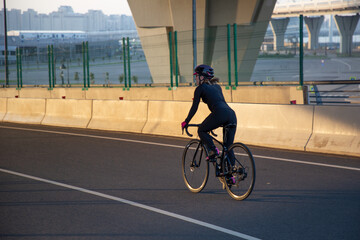 Evening workout of a woman on a bike. Play sports in the city. Yacht Bridge St. Petersburg.