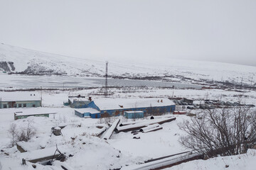 one-story blue building in the snow on the background of mountains in the fog in winter