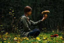 A Woman Sitting In Forest, Holding And Checking Wild Mushrooms In Hand. Risk Of Mushroom Poisoning Concept. Safe Mushroom Hunting, Foraging, Picking, Collecting, Harvesting, Gathering. Mushrooming.