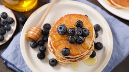 Wall Mural - Pancakes with blueberries and honey on a plate, top view