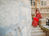 Fototapeta Na drzwi - Beautiful ethnic Indian Saree. Young woman in red, colorful, sensual, wedding and very feminine outfit - Indian sari poses on old streets in India. .Traditional national clothing of Indian women