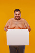 © Mike Orlov - Fat and happy shirtless man displaying a white banner ad isolated over a yellow background.