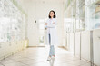 © LIGHTFIELD STUDIOS - full length of smiling asian pharmacist in white coat standing with crossed arms in drugstore