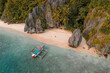 © AmazingAerialAgency - Aerial view of outrigger fishing boat on sandy beach, El Nido, the Philippines.