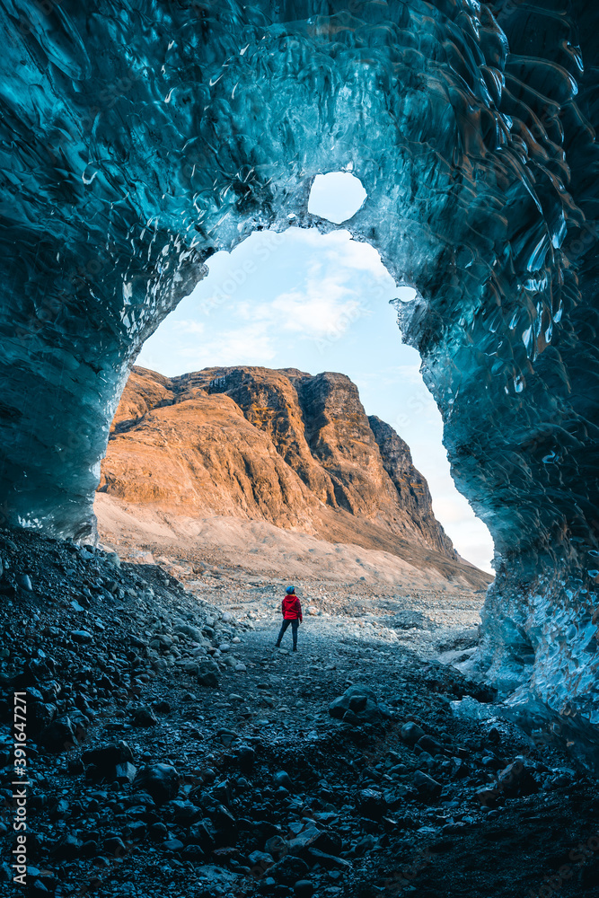Solo female adventure traveler is discovering the ice caves in Iceland at Vatnajokull Glacier near to Jokulsarlon Glacier Lagoon. Tourism in abandoned Iceland . Outdoor living and exploring  - obrazy, fototapety, plakaty 