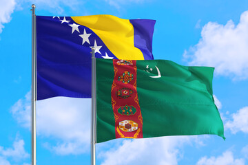 Turkmenistan and Bosnia Herzegovina national flag waving in the windy deep blue sky. Diplomacy and international relations concept.