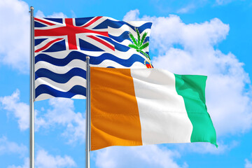 Wall Mural - Cote D'Ivoire and British Indian Ocean Territory national flag waving in blue sky. Diplomacy and international relations concept.