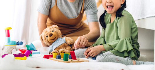 Portrait of enjoy happy love asian family mother and little asian girl smiling playing with toy build wooden blocks board game in moments good time at home