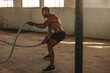 © Jacob Lund - Muscular man doing battle rope workout