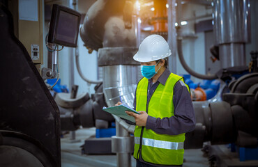 Engineer under checking the industry cooling tower air conditioner is water cooling tower air chiller HVAC of large industrial building to control air system ,wearing mask for protect pollution.