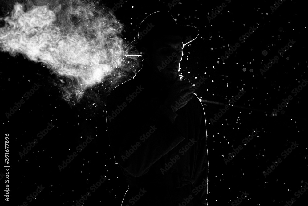 smoke a cigarette in the rain dark silhouette of a man in a hat Smoking a cigarette in the rain Stock  Photo