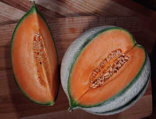 Ripe melon and slice of melon on a wooden board.