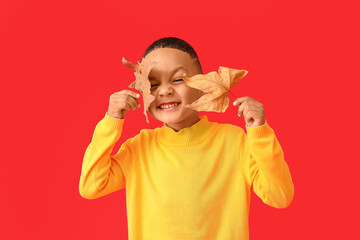 Wall Mural - Cute African-American boy with autumn leaves on color background