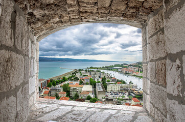 Wall Mural - View from stone window of blue sea and red roofs in historic city center in Omis, Croatia